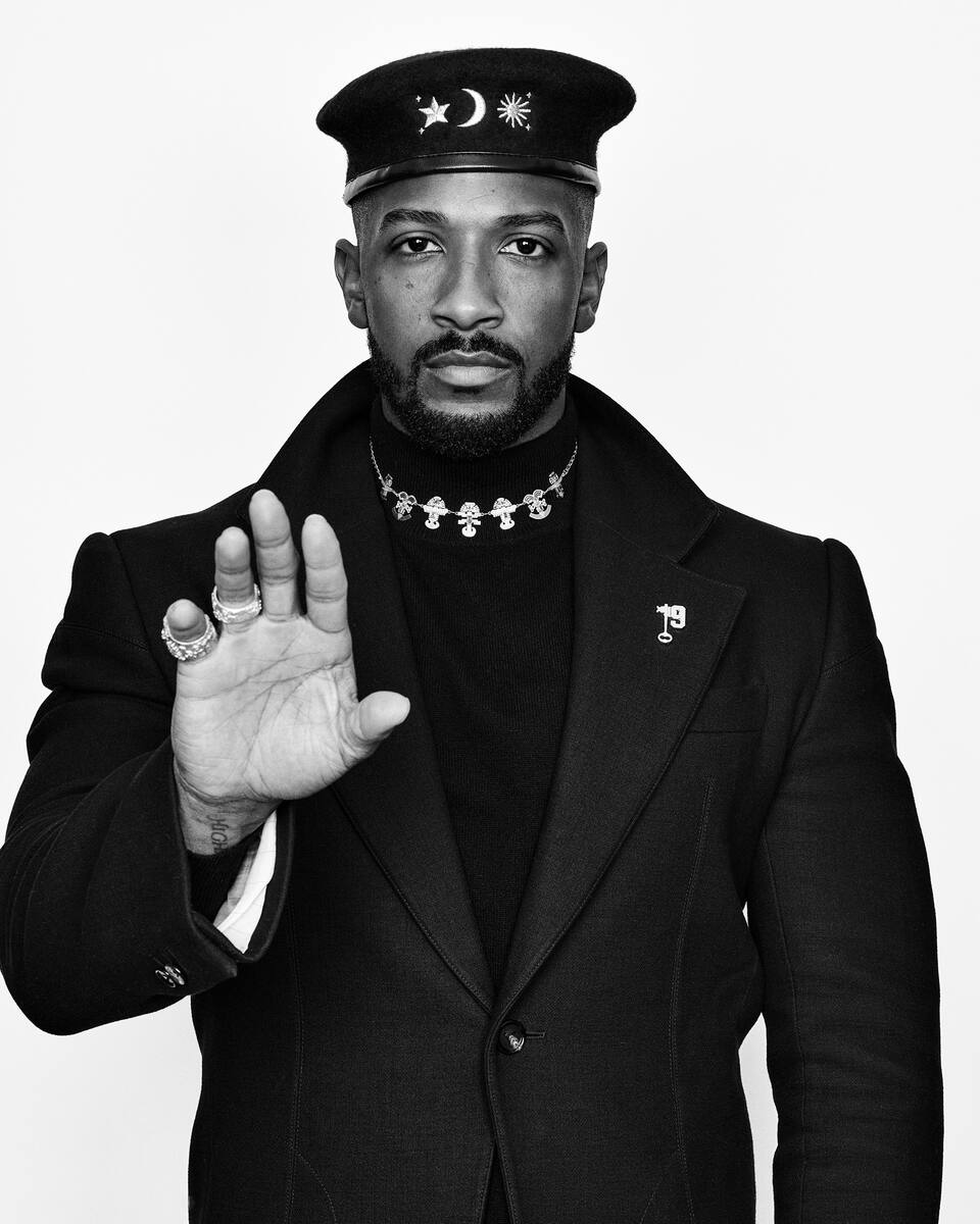 19Keys portrait — palm raised, wearing the star, moon and sun beret